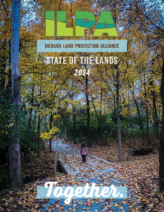 Cover of State of the Lands publication. ILPA logo is centered in the top third with the title, State of the Lands 2024 in a white font. Background photo shows a small child standing on a wooden boardwalk crossing a small creek in a young forest. The trees are small and still tower over the small person in the image. The trees have turned golden and leaves cover the ground around the trail and water.